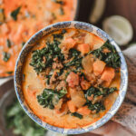 holding a bowl of chorizo and sweet potato soup